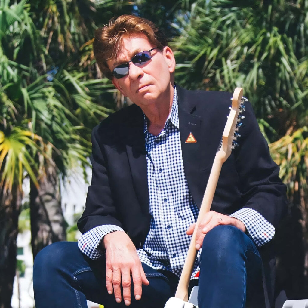 Bobby Caldwell in blazer and sunglasses holding guitar outdoors before live performance wallpaper