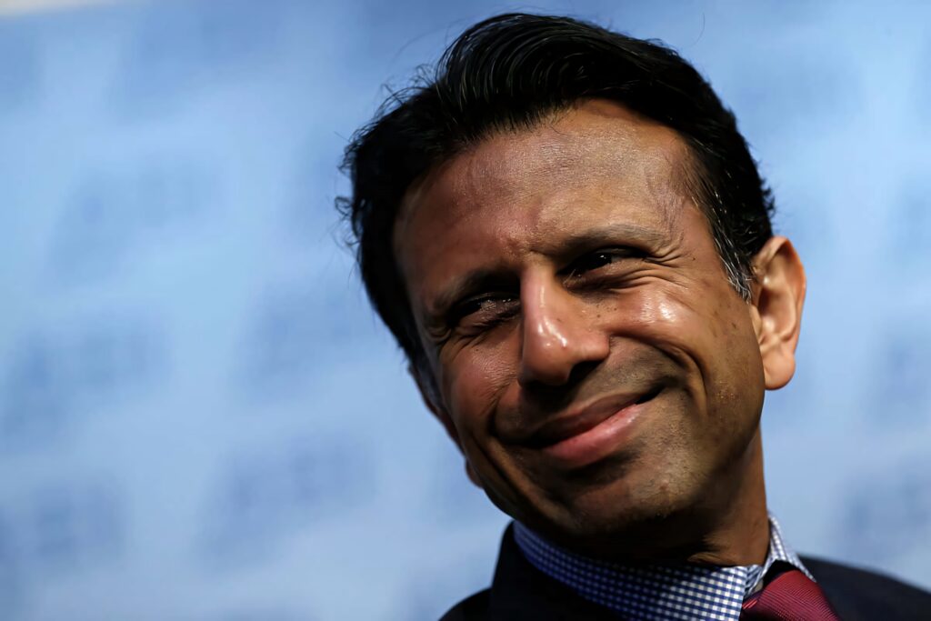 Bobby Jindal smirking confidently with soft blue blurred background political wallpaper