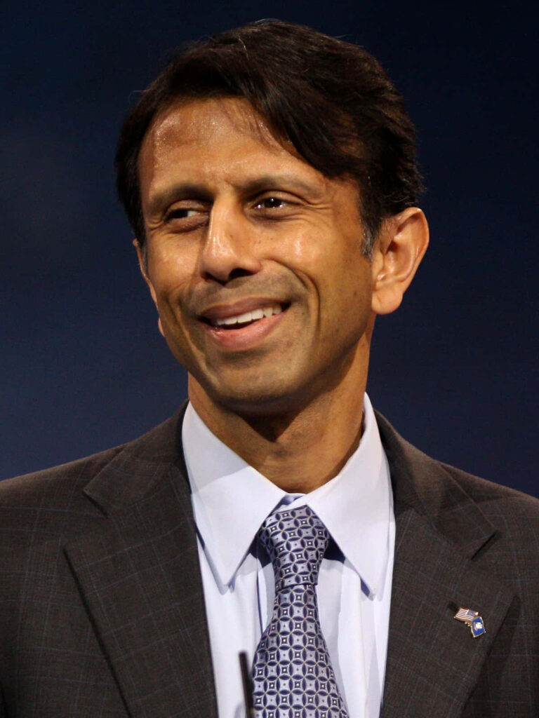 Bobby Jindal smiling in professional suit and tie with calm approachable expression wallpaper background