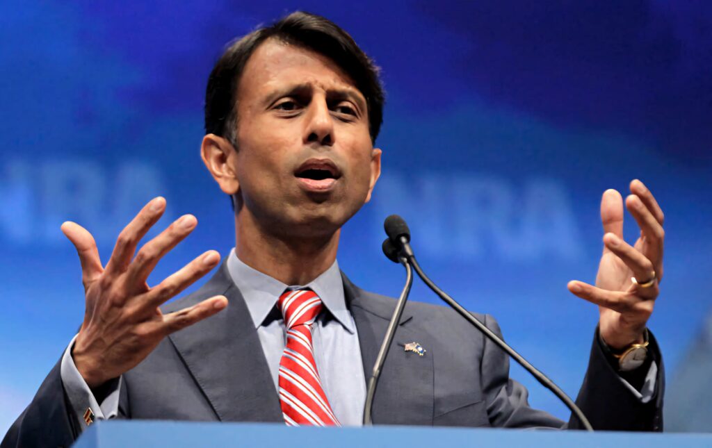 Bobby Jindal speaking passionately at NRA event mid-gesture bold blue background wallpaper