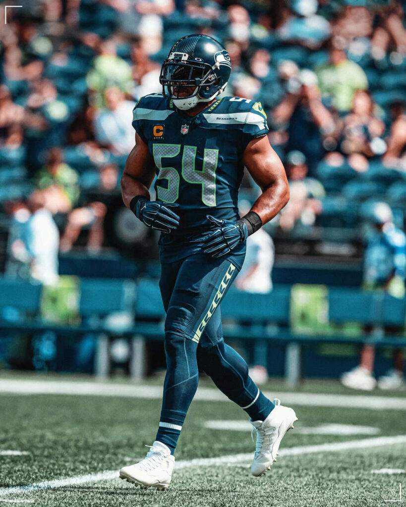 Bobby Wagner in Seattle Seahawks uniform standing on football field with stadium crowd background Wallpaper