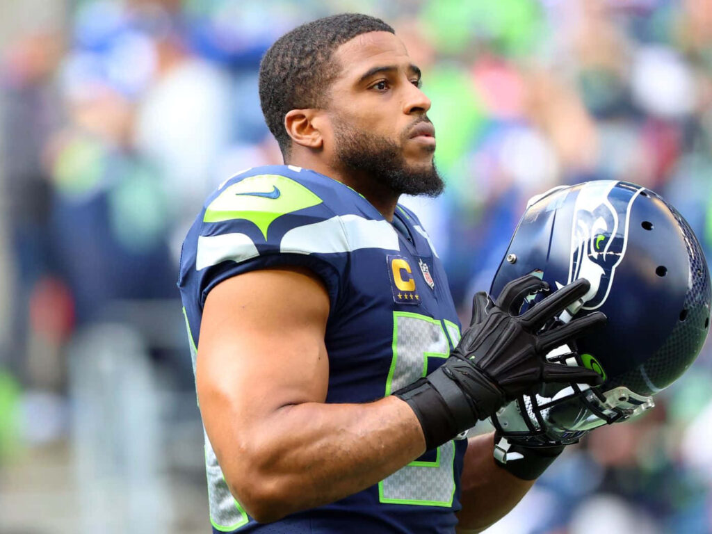 Bobby Wagner in Seattle Seahawks uniform holding helmet showing focus and linebacker intensity Wallpaper
