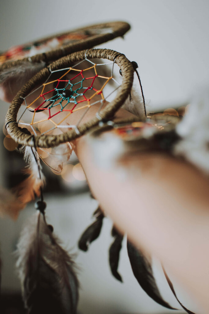 Woman holding handcrafted colorful dream catcher with feathers close-up bohemian style wallpaper