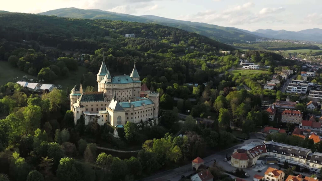 Aerial view of Bojnice Castle surrounded by lush forest and scenic Slovak village landscape Wallpaper