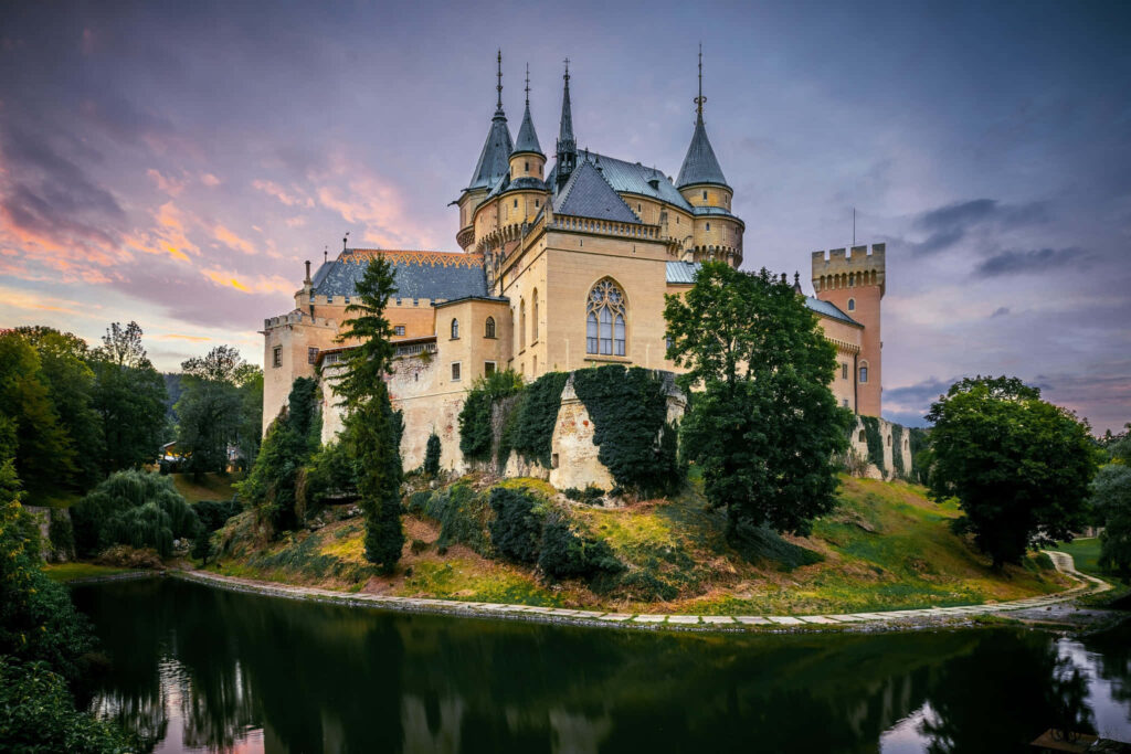 Bojnice Castle medieval sunset Slovakia lush greenery reflective moat historic landscape wallpaper