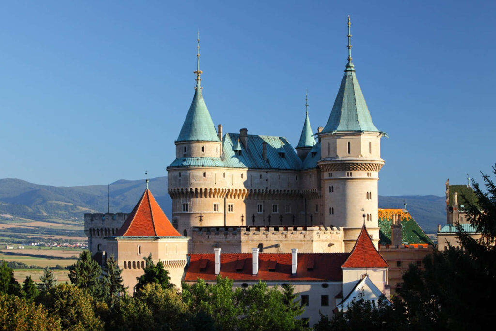 Bojnice Castle roofs with teal spires red tiles stone towers scenic mountain background wallpaper