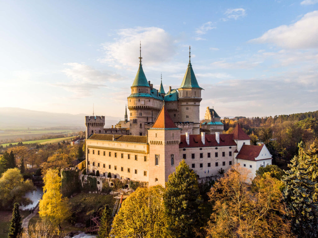 Bojnice Castle in Slovakia surrounded by autumn trees and golden sunlight scenic medieval view Wallpaper