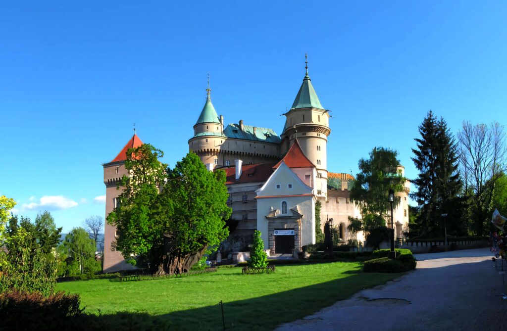 Bojnice Castle Slovakia with turquoise towers lush gardens and clear blue sky wallpaper background