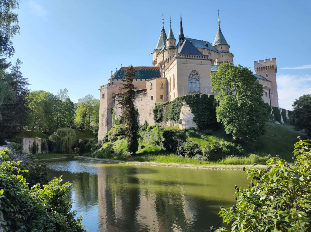 Bojnice Castle medieval architecture reflected in pond surrounded by green grass and trees wallpaper