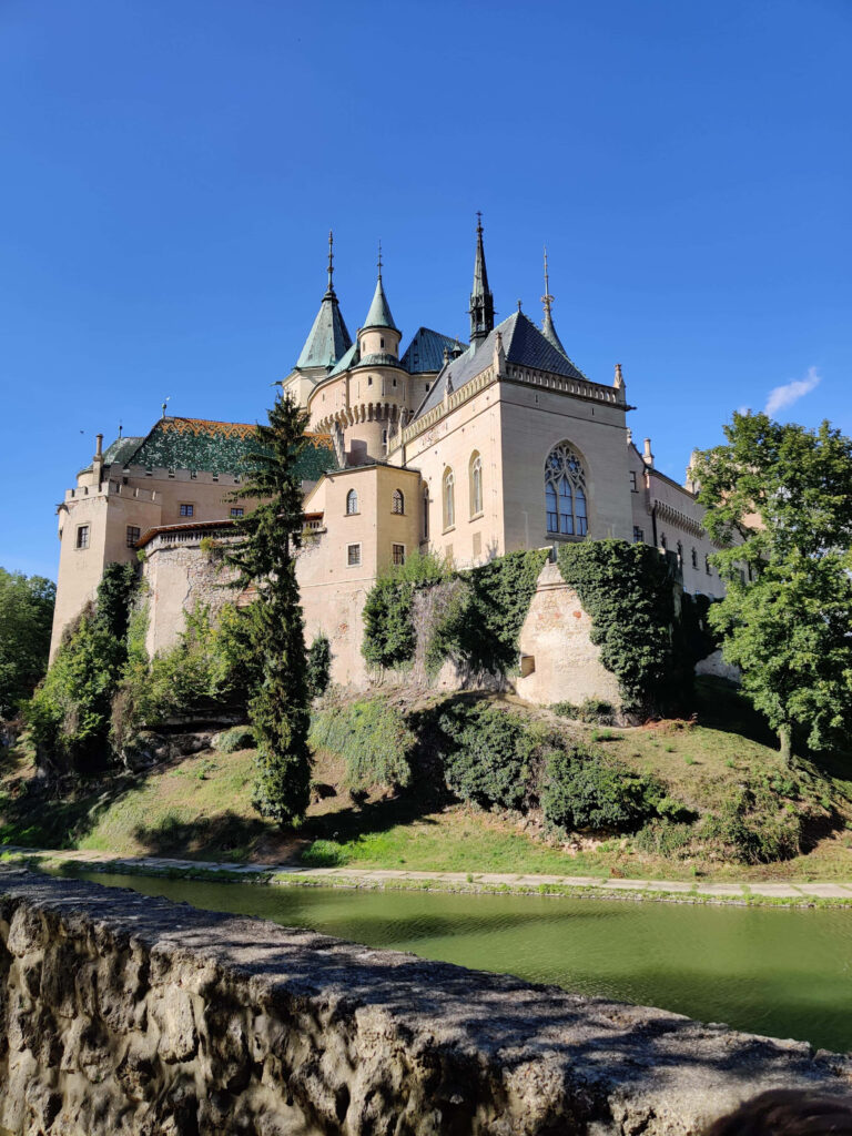 Bojnice Castle medieval fortress in Slovakia with ivy towers and serene moat under blue sky Wallpaper