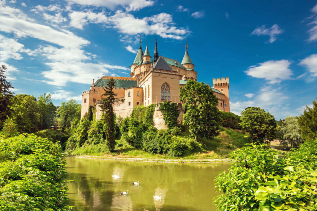 Bojnice Castle Slovakia medieval architecture reflected in water with blue sky and green trees Wallpaper
