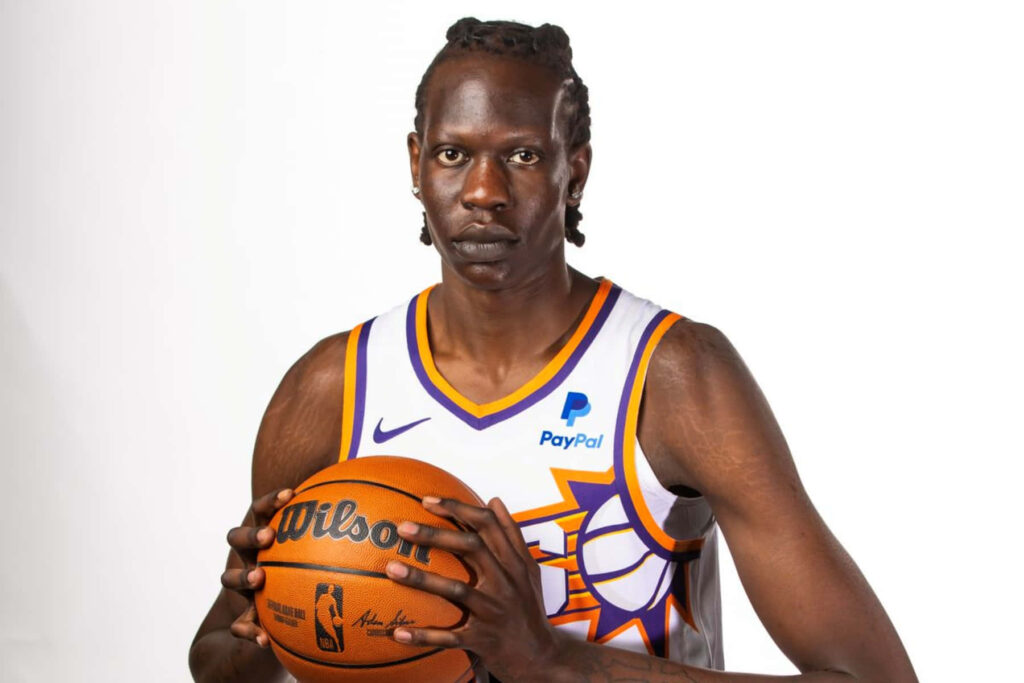 Bol Bol portrait holding basketball in white Phoenix Suns jersey on white background wallpaper