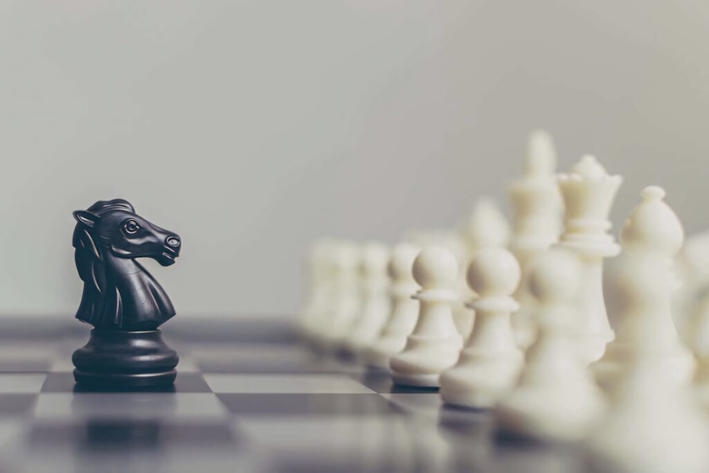Black knight chess piece faces white pieces on classic board dramatic strategic wallpaper background