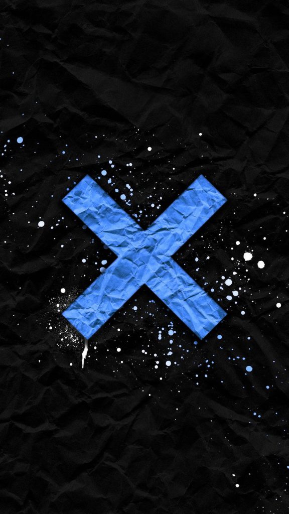 Crumpled blue letter X with white paint splatters on dark textured black urban wallpaper background