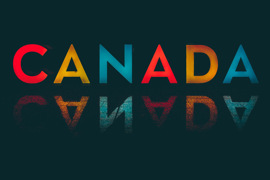Bold colorful CANADA text with red yellow blue gradient reflected on dark background wallpaper