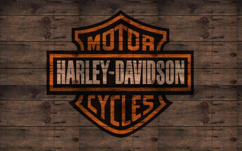 Harley-Davidson Motor Cycles logo bright orange on rustic dark wood plank background wallpaper