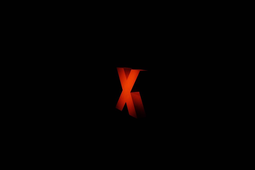 3D red letter X glowing on black background minimalist modern digital wallpaper design