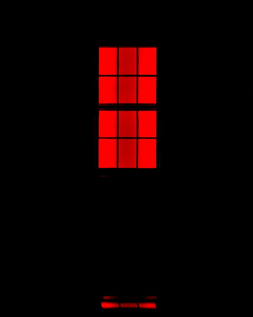Bold Red-Lit Window Wallpaper: Striking Lattice Design on Black