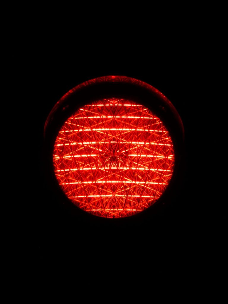 Red traffic light glowing with geometric texture on black background minimalist wallpaper design