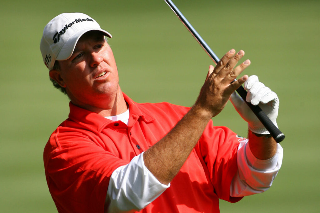 Boo Weekley watching golf ball in red polo on vibrant green golf course wallpaper background