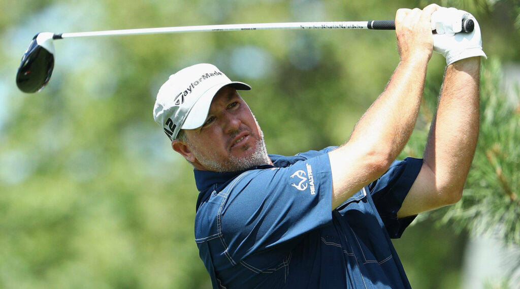 Boo Weekley mid-swing on lush green golf course wearing navy polo and white cap wallpaper