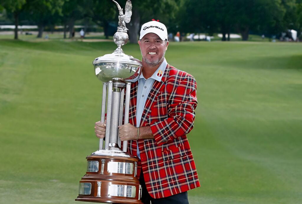Boo Weekley holding silver trophy on green golf course wearing red plaid winner jacket outdoors Wallpaper