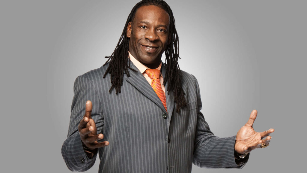 Booker T WWE Superstar in pinstripe suit and orange tie on smooth grey background wallpaper