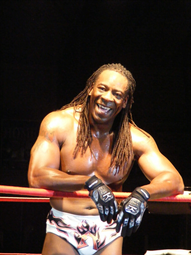 Booker T in TNA ring with braided hair and red ropes under arena lighting dynamic sports scene Wallpaper
