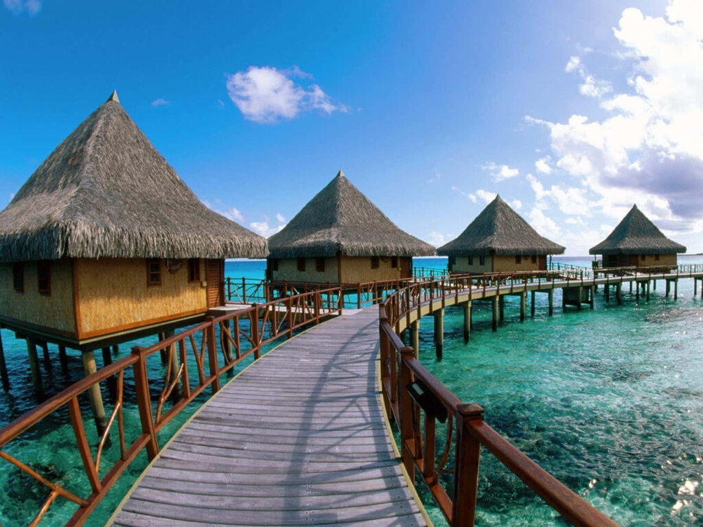 Bora Bora overwater bungalows on turquoise waters under bright blue sky tropical paradise wallpaper