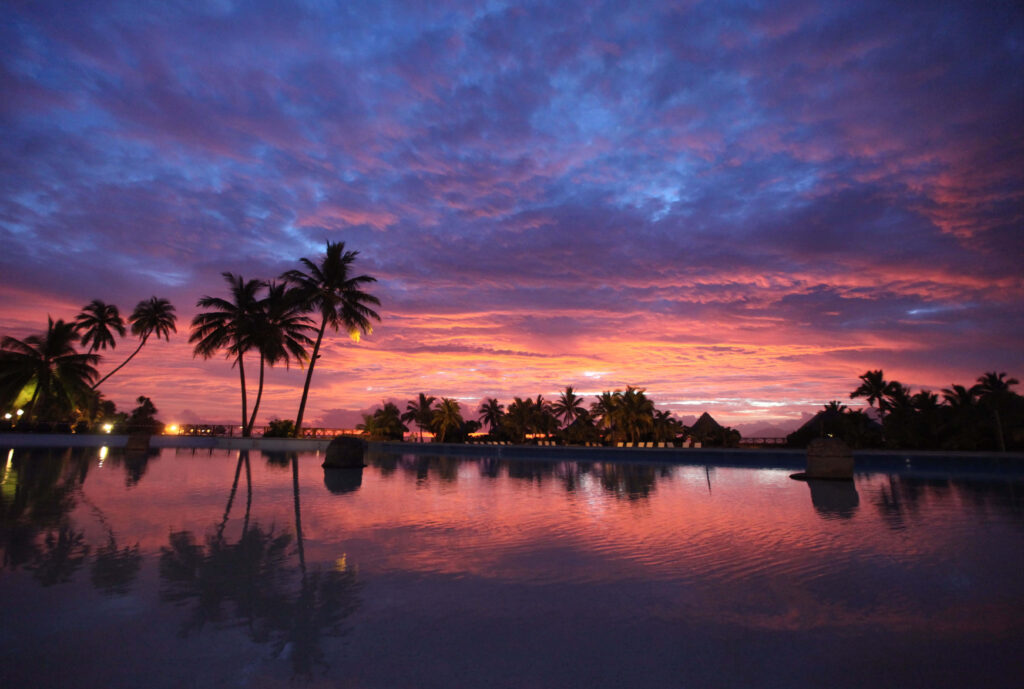 Sunset over serene pool with palm trees in tropical Bora Bora capturing tranquil beauty Wallpaper