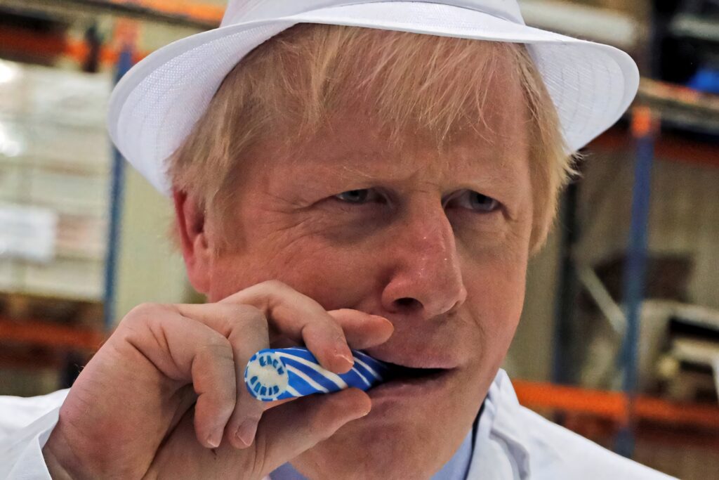 Boris Johnson holding blue and white candy cane in lab coat and white hat industrial holiday wallpaper