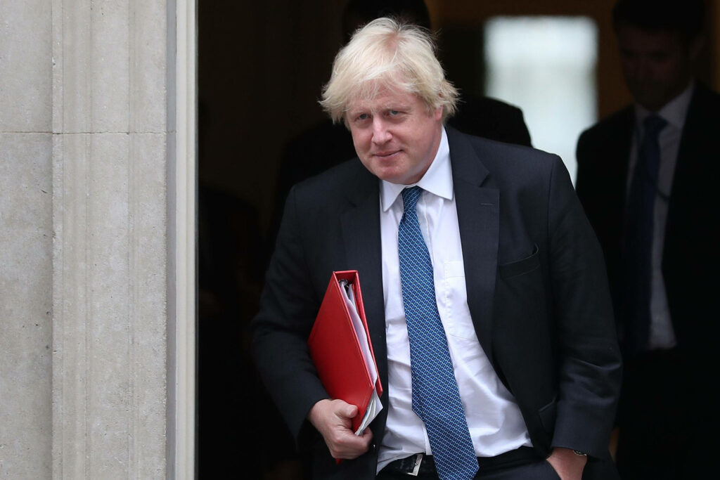 Boris Johnson in suit holding red folder outside UK government building political leadership wallpaper