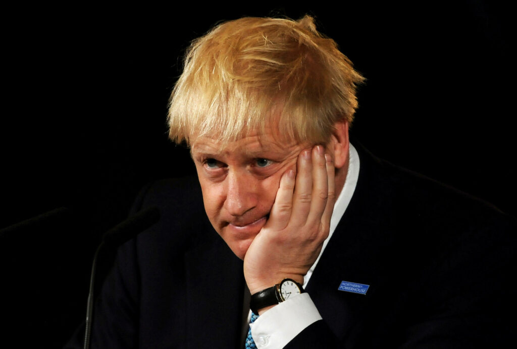 Boris Johnson close-up portrait with thoughtful pout messy blond hair dark background wallpaper