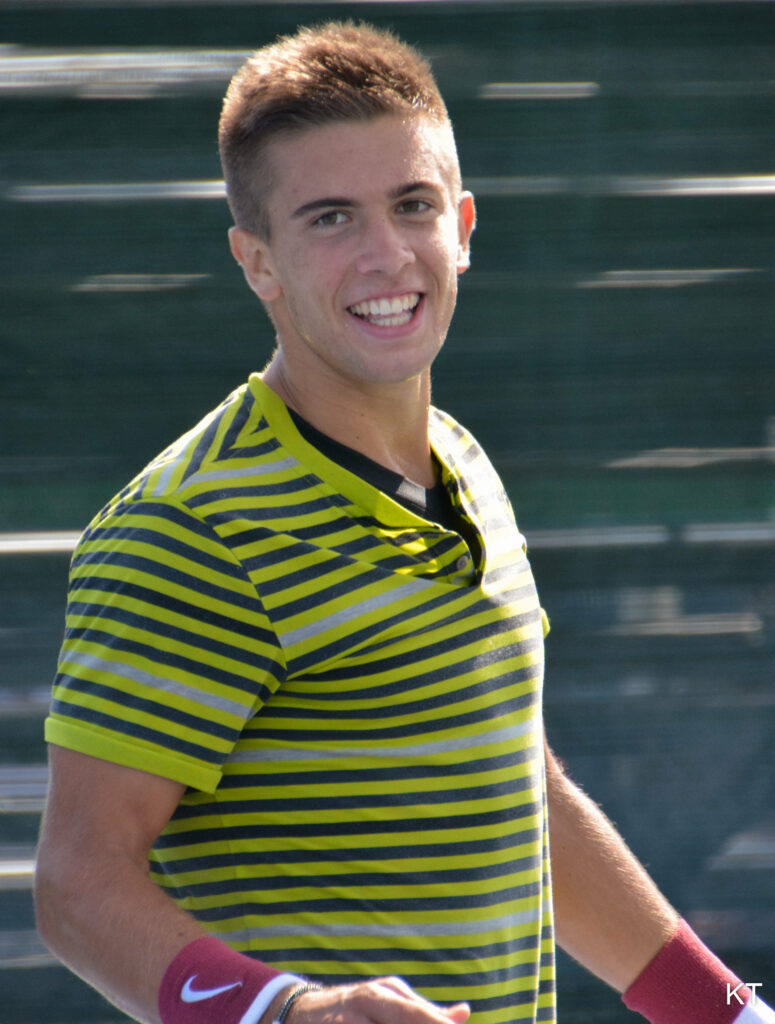 Borna Coric smiling in green yellow striped shirt vibrant tennis player wallpaper background