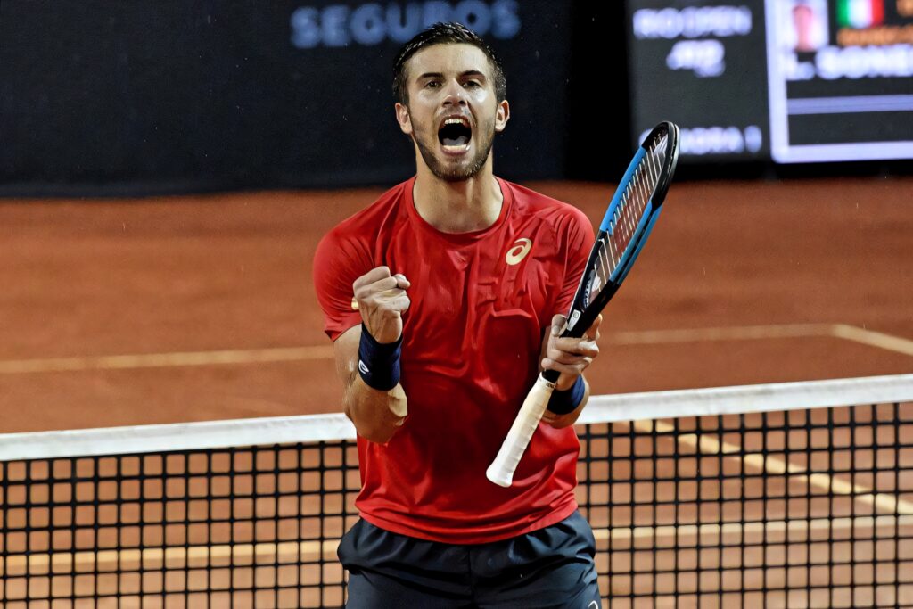 Borna Coric celebrates intense victory in red attire on clay court vibrant tennis action wallpaper