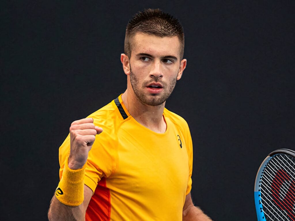 Borna Coric in yellow sports shirt victorious fist pump dark background high energy tennis wallpaper