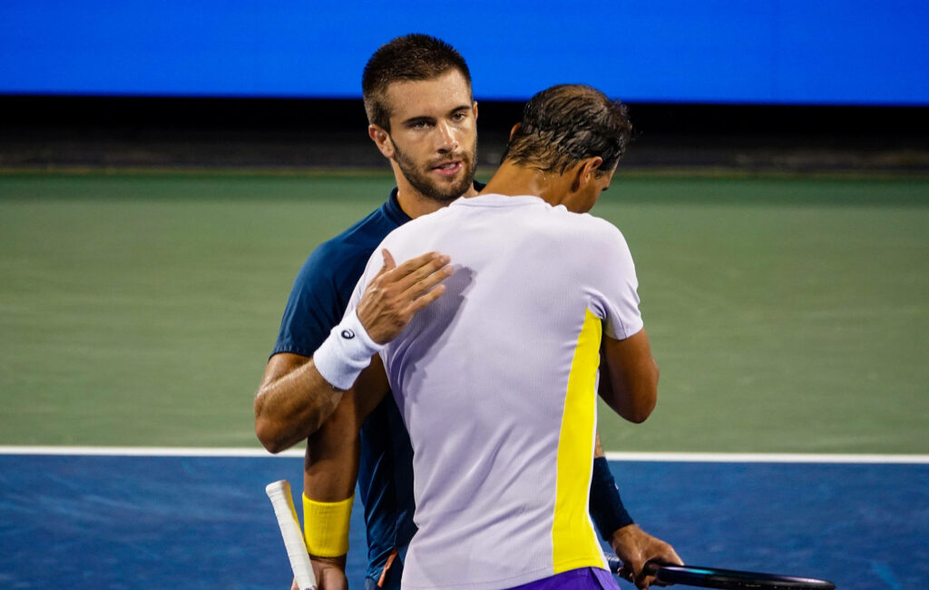 Borna Coric and Rafael Nadal tennis action wallpaper with vibrant blue green background tones