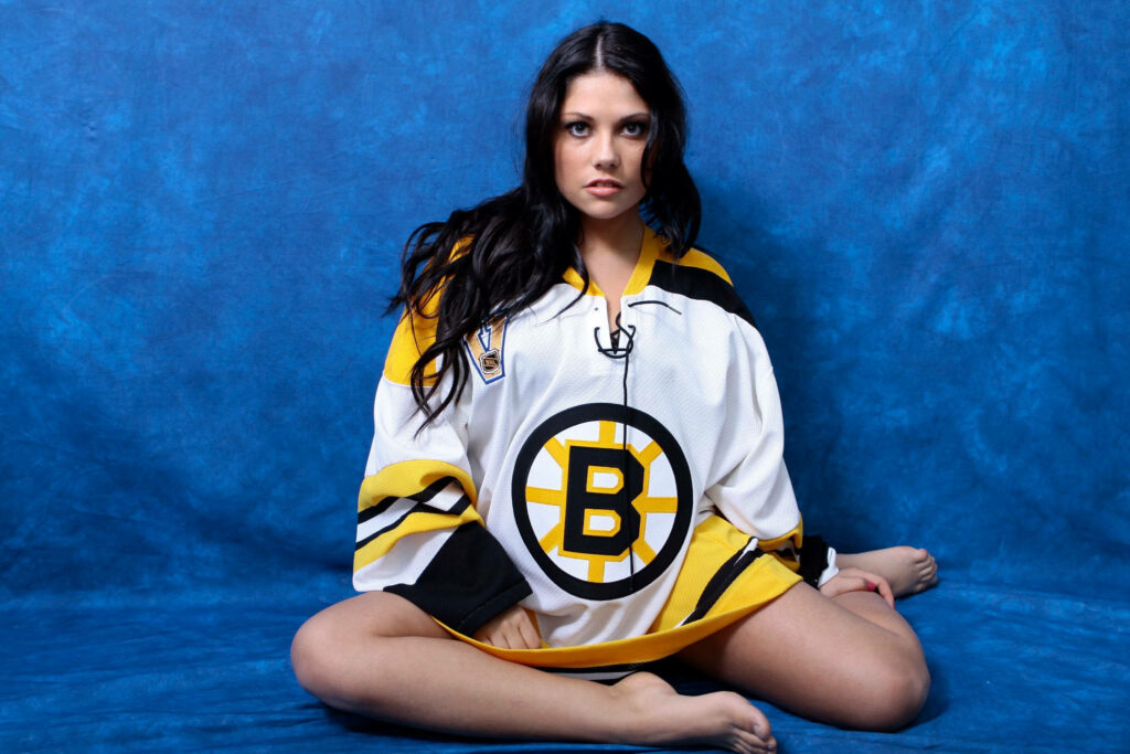 Young Boston Bruins fangirl in oversized jersey on vibrant blue background sports fan wallpaper