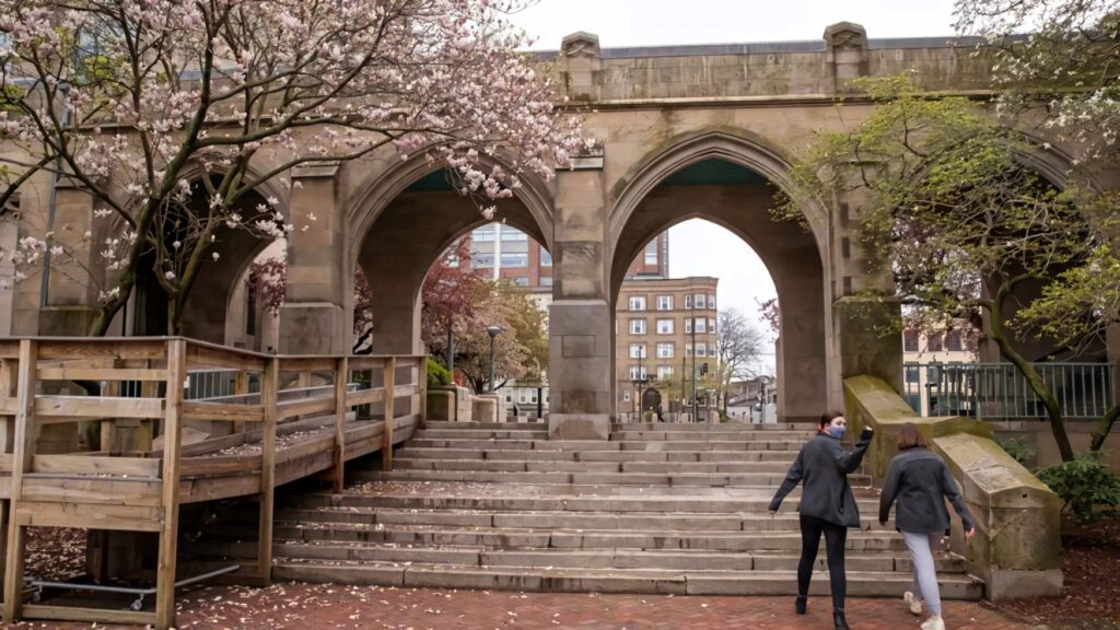 Boston University Campus with historic stone arches blossoming trees and students walking in spring Wallpaper