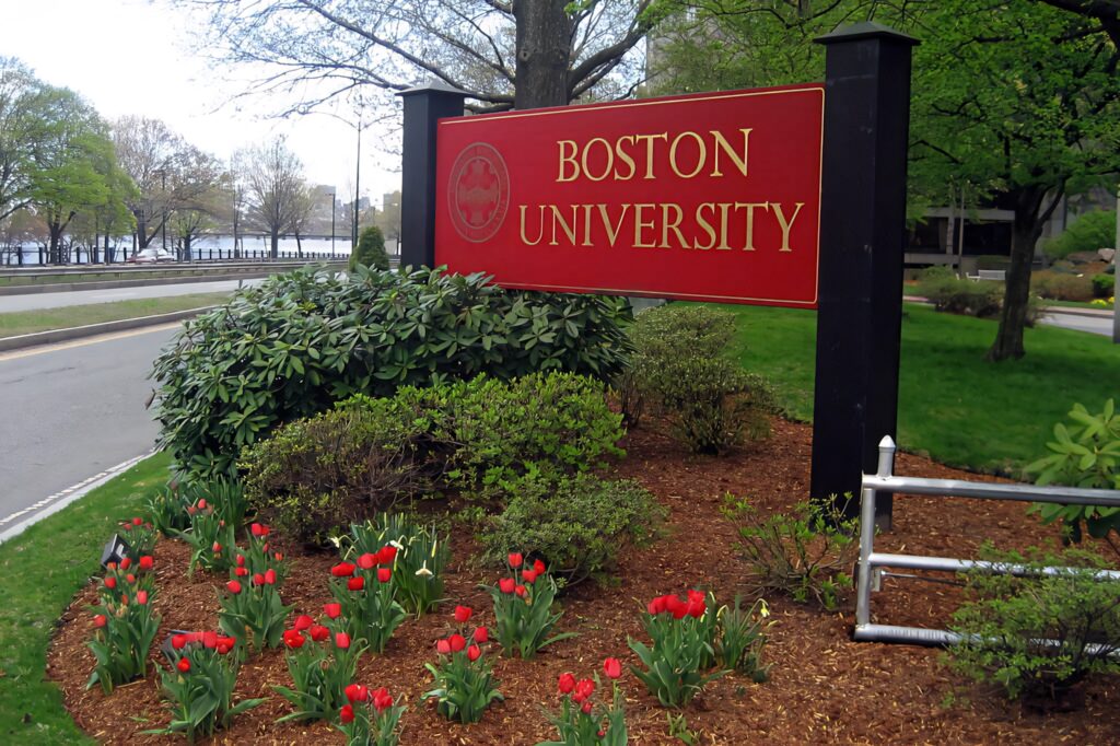 Boston University roadside sign with red logo green landscaping and blooming tulips in spring Wallpaper