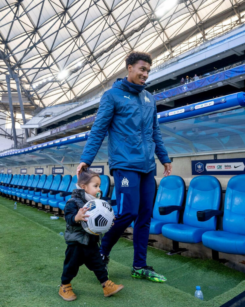 Boubacar Kamara walking hand in hand with daughter on stadium field sunny day family moment wallpaper