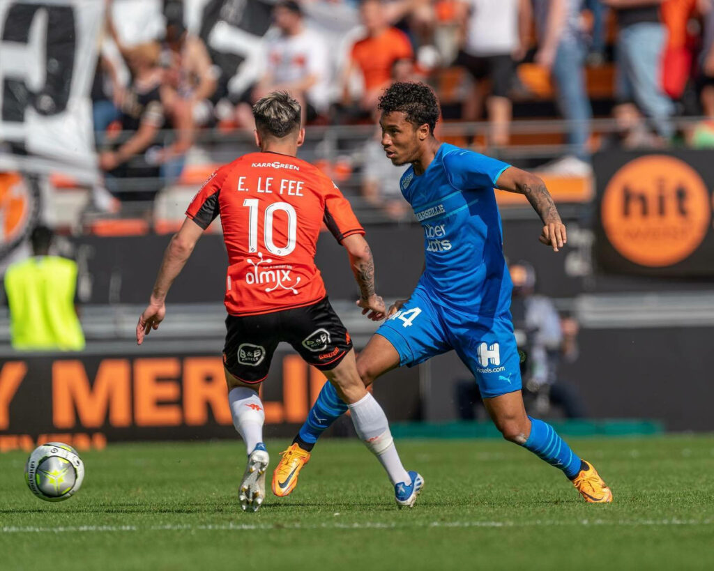 Boubacar Kamara in blue jersey and Enzo Le Fée in orange kit duel during vibrant Ligue 1 football match Wallpaper
