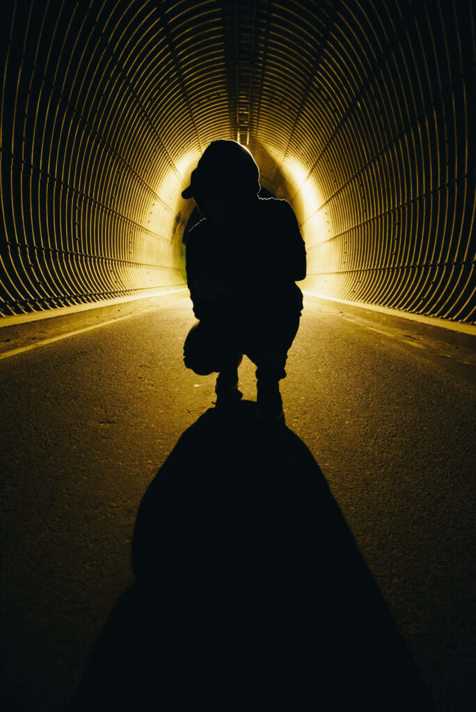 The Illuminated Journey: A Young Adventurer Emerging from the Shadows in a Mysterious Underground Passage Wallpaper