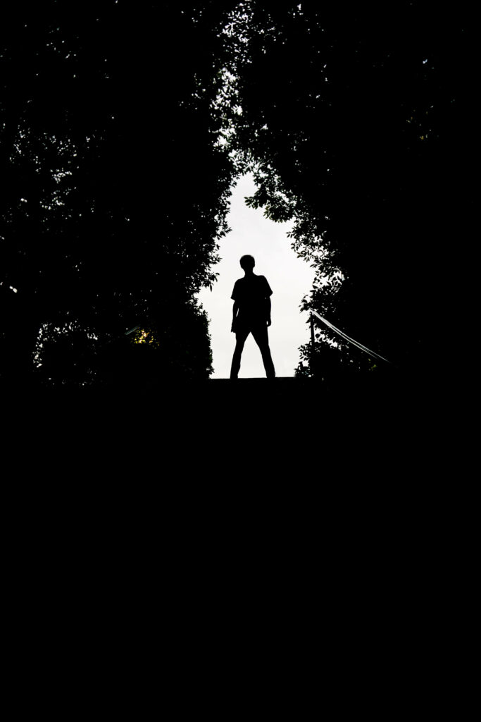 Boy Silhouette Wallpaper Amidst Dark Foliage - Mysterious Scene