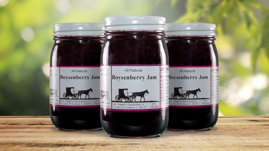 Three jars of rich boysenberry jam with rustic labels against sunlit green background wallpaper