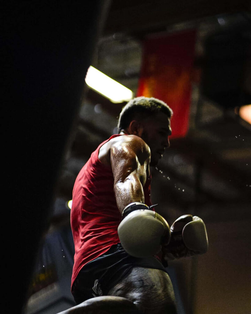 Brad Tavares intense boxing training in red tank top showcasing muscular physique gym background Wallpaper