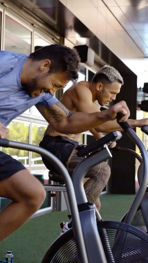 Brad Tavares intense MMA training on exercise bike showcasing athleticism and focus in gym Wallpaper