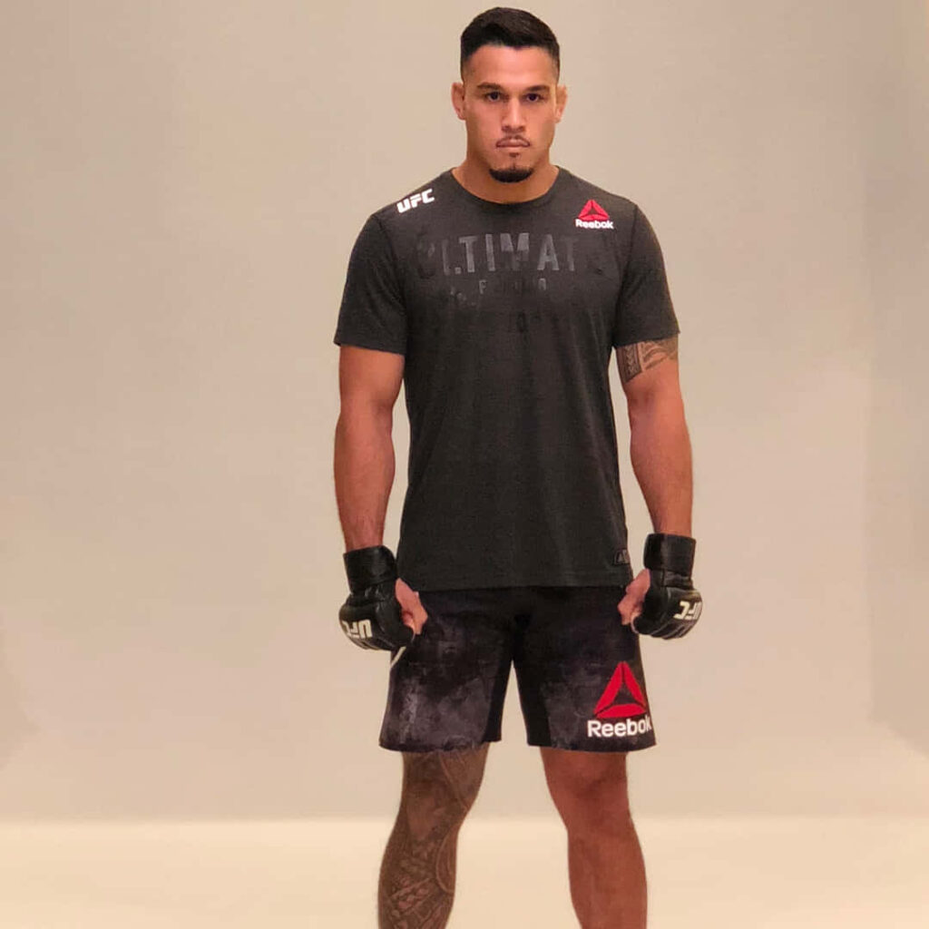 UFC fighter Brad Tavares in gray Reebok outfit standing confidently MMA athlete wallpaper background