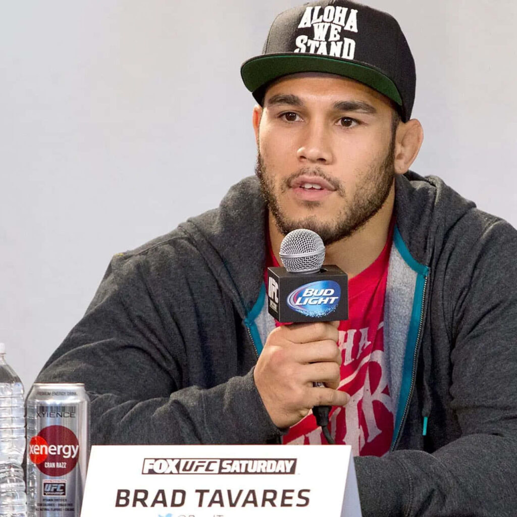 Brad Tavares UFC fighter speaking at press conference holding microphone in black cap and hoodie Wallpaper