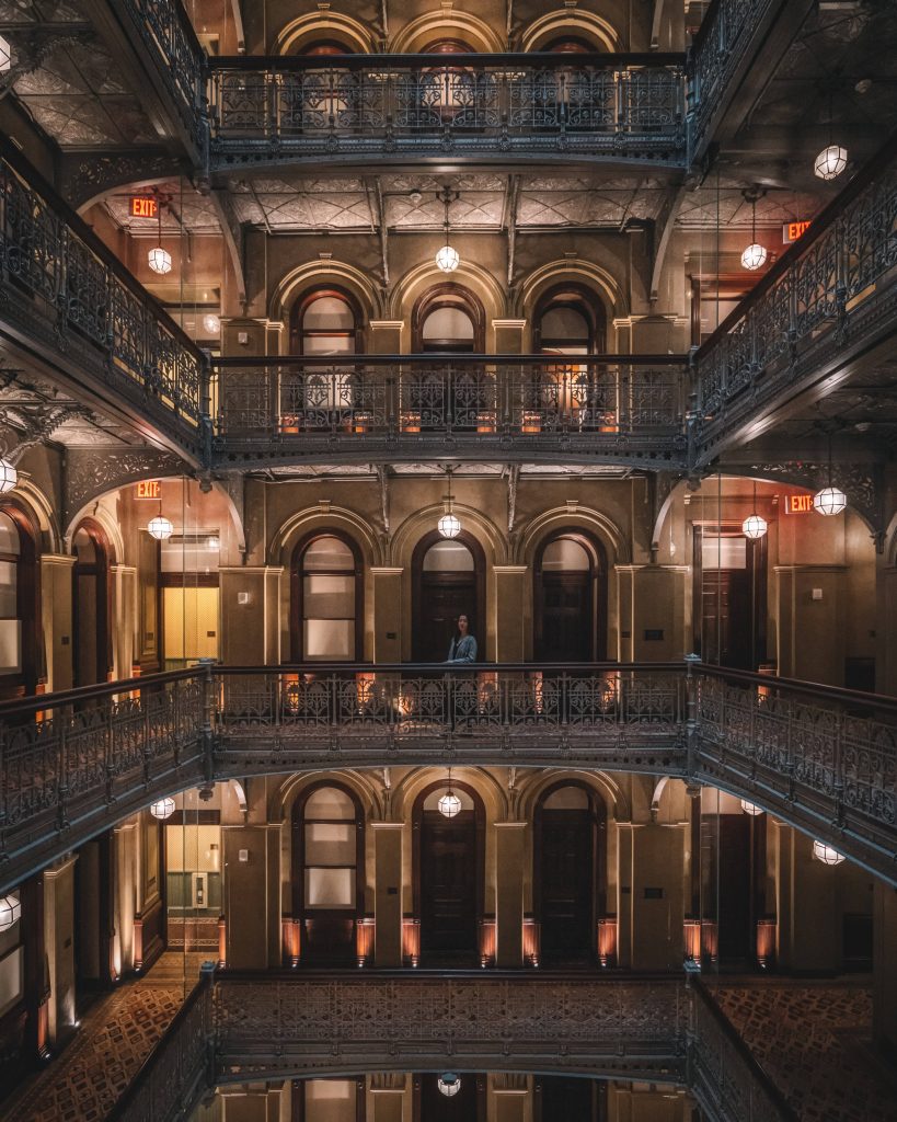 Bradbury Building interior Los Angeles ornate iron railings warm lighting multiple levels symmetrical view Wallpaper